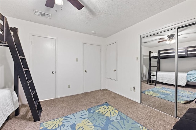 carpeted bedroom featuring a textured ceiling, a closet, and ceiling fan