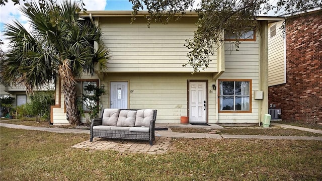 view of front of house with a front yard and cooling unit