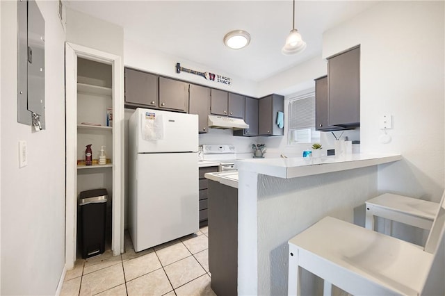 kitchen featuring kitchen peninsula, light tile patterned floors, decorative light fixtures, and white appliances