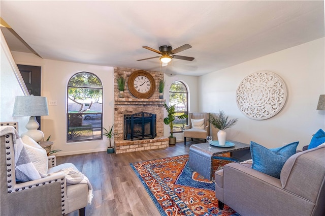 living room featuring wood-type flooring, ceiling fan, and a fireplace