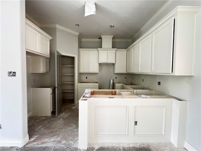 kitchen with baseboards, ornamental molding, and white cabinets