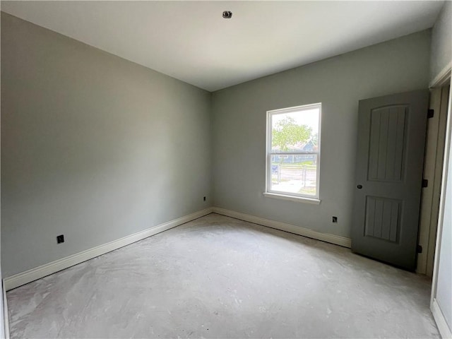 spare room with baseboards and concrete flooring