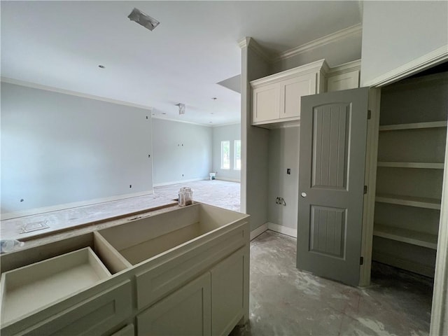 kitchen with crown molding, concrete flooring, white cabinets, and baseboards