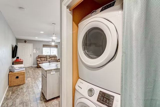 clothes washing area featuring stacked washer / drying machine, ceiling fan, and light hardwood / wood-style floors