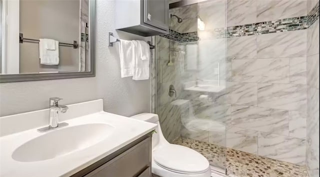 bathroom featuring vanity, toilet, and tiled shower