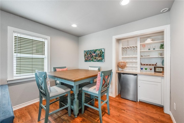 dining room with baseboards, a bar, light wood-style flooring, and recessed lighting