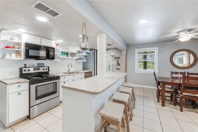 kitchen featuring visible vents, appliances with stainless steel finishes, a breakfast bar, open shelves, and a sink