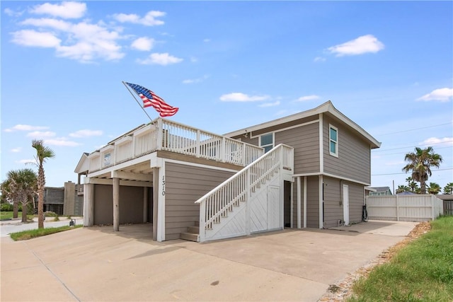 view of front of property with fence, concrete driveway, stairway, a wooden deck, and a patio area