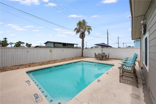 pool with outdoor dining area, a patio area, and a fenced backyard