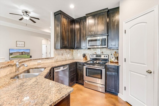 7237 Lake Tranquility Dr, Corpus Christi, TX 78414 - kitchen featuring arched walkways, a sink, backsplash, light stone counters, and appliances with stainless steel finishes