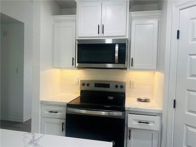 kitchen featuring decorative backsplash, light stone countertops, white cabinets, and range with electric stovetop