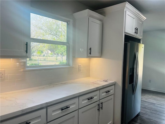 kitchen featuring light stone countertops, white cabinets, dark hardwood / wood-style flooring, tasteful backsplash, and stainless steel fridge