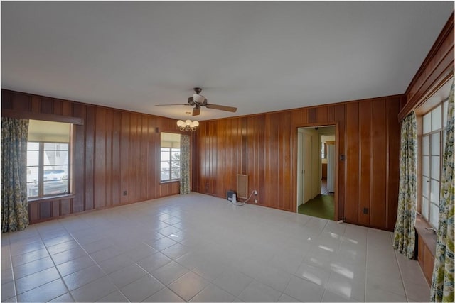 unfurnished room with ceiling fan and wooden walls