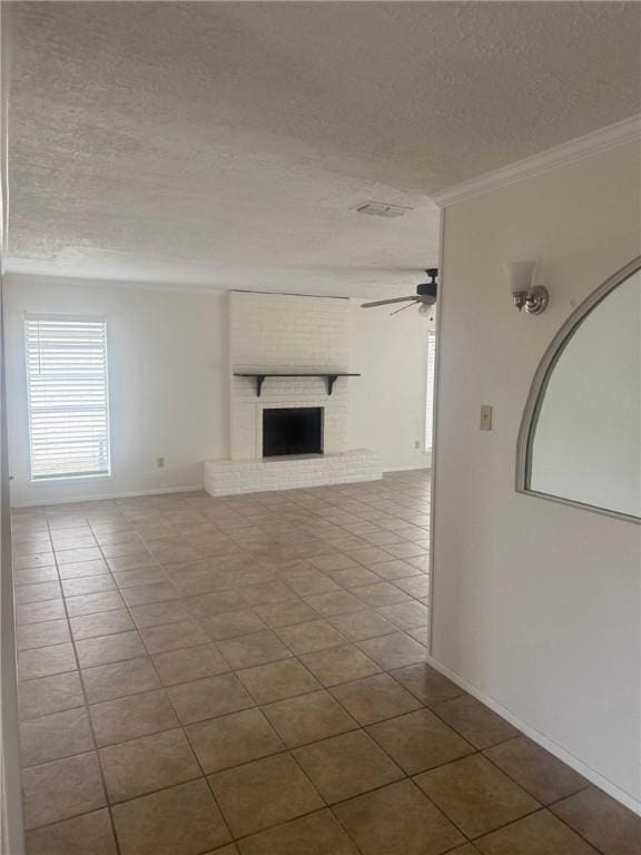 unfurnished living room featuring ceiling fan, ornamental molding, tile patterned floors, a textured ceiling, and a fireplace