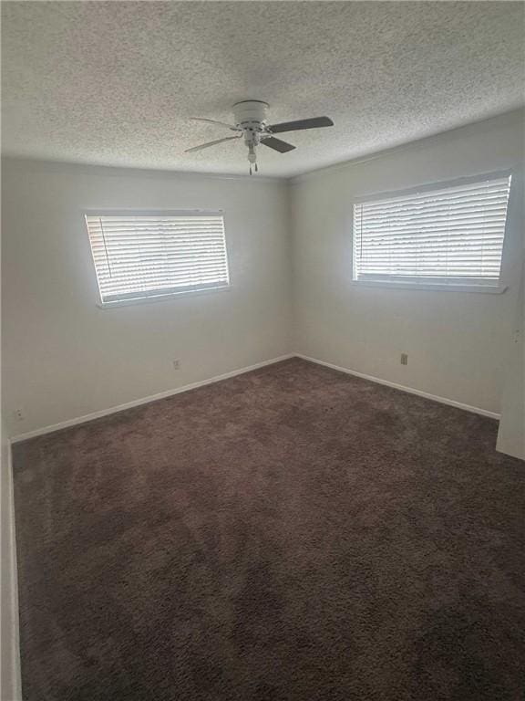 spare room with ceiling fan, baseboards, dark colored carpet, and a textured ceiling