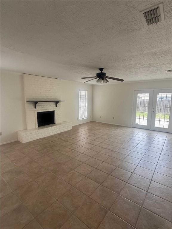 unfurnished living room featuring french doors, a fireplace, visible vents, ceiling fan, and a textured ceiling