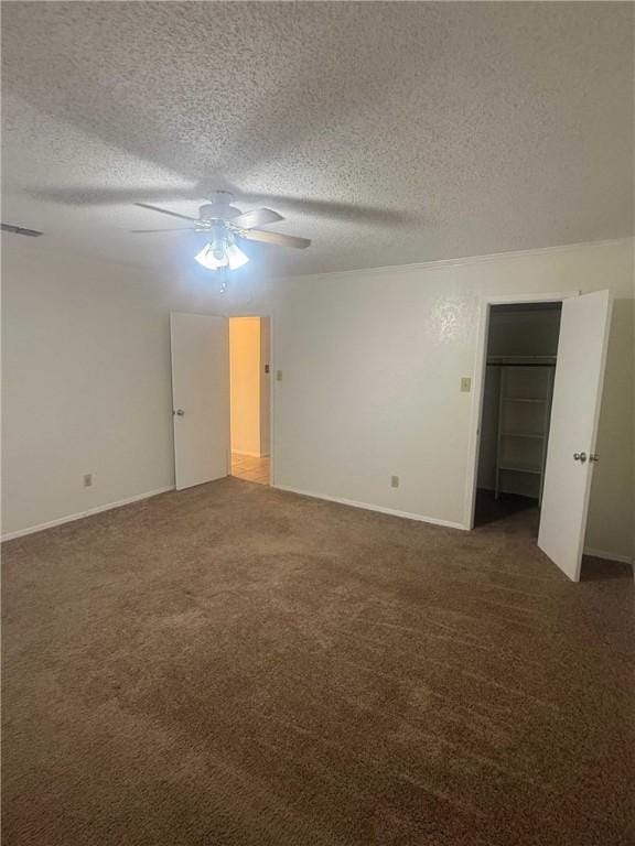 unfurnished room featuring ceiling fan, a textured ceiling, visible vents, baseboards, and dark carpet