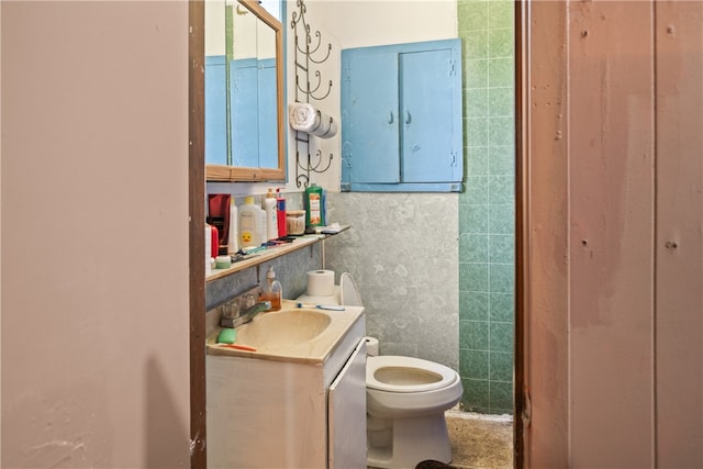 bathroom featuring vanity, toilet, and tile walls