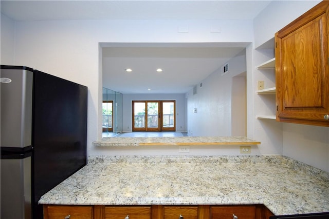 kitchen with light stone counters, stainless steel fridge, and kitchen peninsula