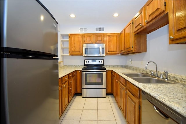 kitchen featuring light stone countertops, light tile patterned flooring, appliances with stainless steel finishes, and sink