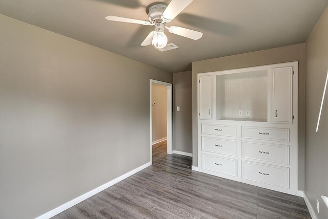 unfurnished bedroom with dark wood-type flooring, visible vents, ceiling fan, and baseboards