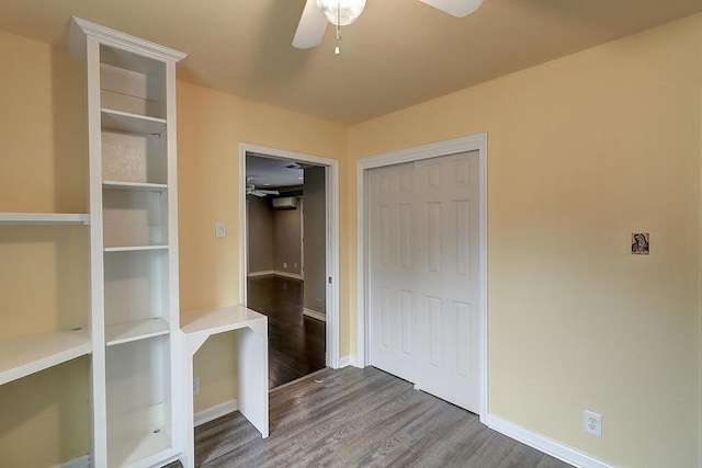 interior space featuring a ceiling fan, a closet, baseboards, and wood finished floors