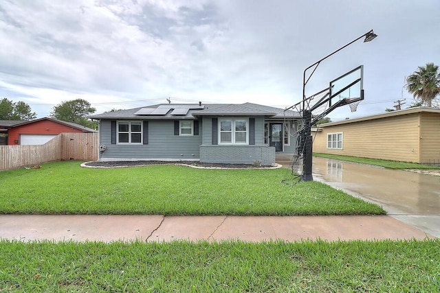 view of front facade with a front yard, fence, and solar panels