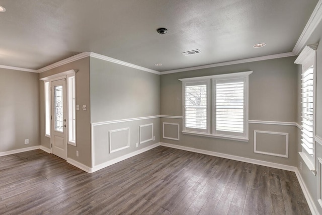 spare room featuring dark wood-type flooring, a healthy amount of sunlight, visible vents, and crown molding