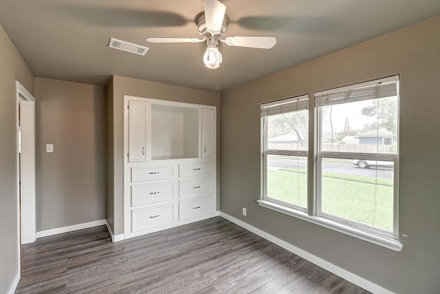 unfurnished bedroom with a ceiling fan, visible vents, baseboards, and dark wood-type flooring