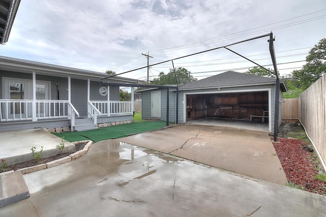 view of front facade with an outbuilding, a shingled roof, a porch, fence, and a garage