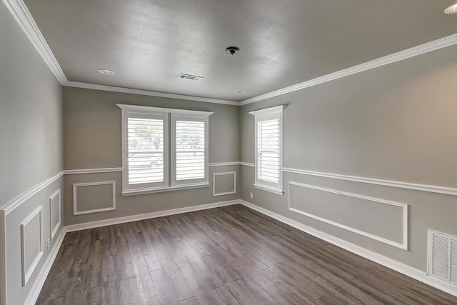 spare room with a decorative wall, visible vents, dark wood finished floors, and ornamental molding