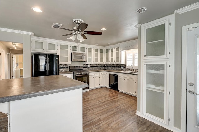 kitchen featuring visible vents, dark wood-type flooring, white cabinets, a sink, and black appliances