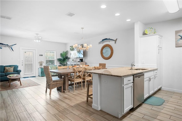 kitchen featuring dishwasher, wood tiled floor, visible vents, and a sink