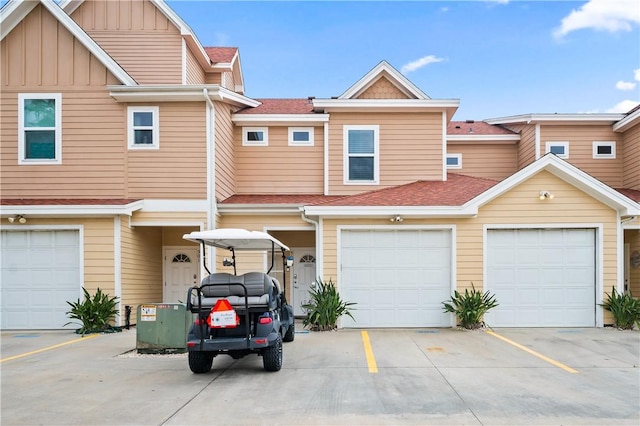 townhome / multi-family property with board and batten siding, driveway, and roof with shingles