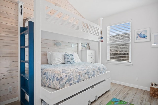 bedroom with vaulted ceiling, baseboards, and wood finish floors