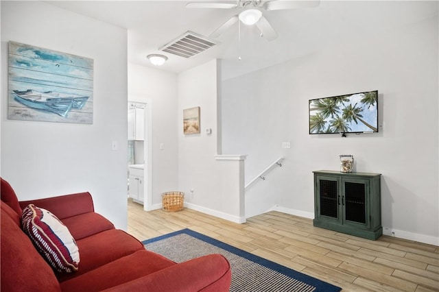 living room featuring light wood-type flooring, visible vents, baseboards, and a ceiling fan