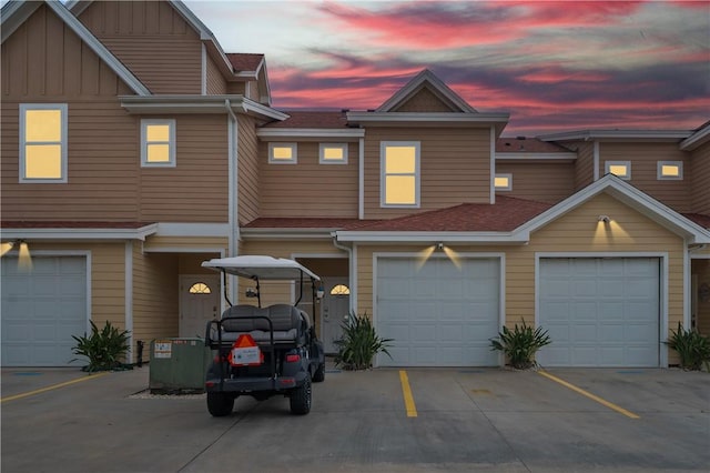 view of property featuring an attached garage, board and batten siding, driveway, and a shingled roof