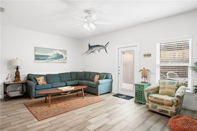 living area featuring visible vents, a ceiling fan, and wood finish floors