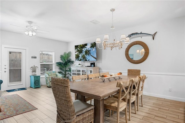 dining room featuring a wainscoted wall, ceiling fan with notable chandelier, and light wood-style floors