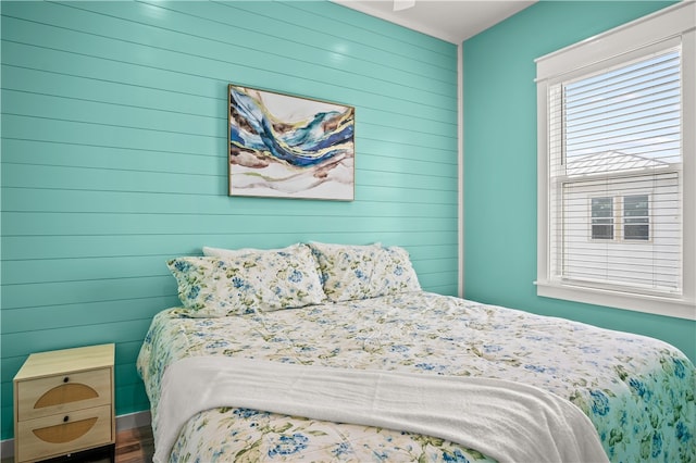 bedroom with wood walls and hardwood / wood-style flooring