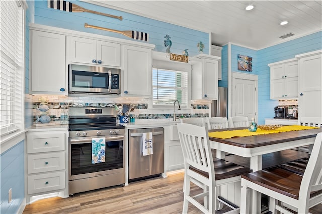 kitchen featuring sink, light hardwood / wood-style flooring, appliances with stainless steel finishes, tasteful backsplash, and white cabinetry