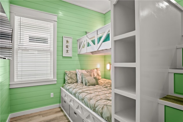 bedroom with light hardwood / wood-style flooring and wooden walls