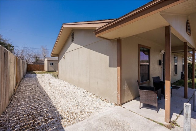 view of side of home with a patio area, a fenced backyard, and stucco siding