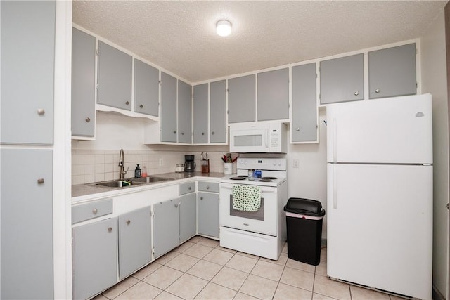 kitchen with light tile patterned floors, gray cabinetry, white appliances, a sink, and backsplash