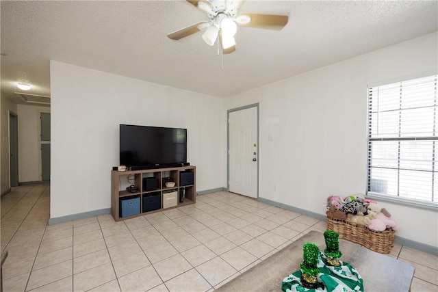 living room featuring light tile patterned floors, ceiling fan, a textured ceiling, and baseboards