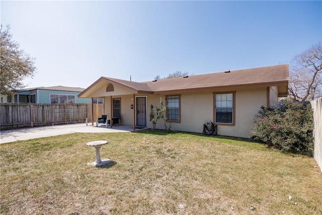 view of front facade with fence, a front lawn, a patio, and stucco siding