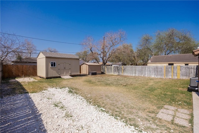 view of yard with a storage shed, a fenced backyard, central AC unit, and an outdoor structure