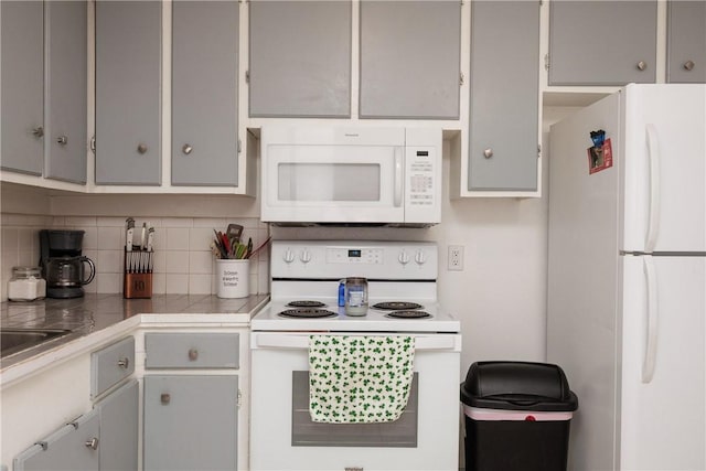 kitchen featuring white appliances, gray cabinets, and tasteful backsplash