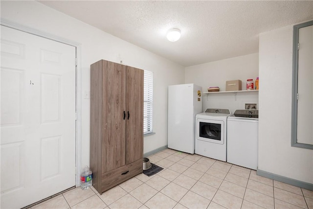 clothes washing area featuring laundry area, light tile patterned floors, baseboards, washer and clothes dryer, and a textured ceiling