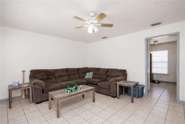 living area with light tile patterned floors, a ceiling fan, visible vents, and a textured ceiling